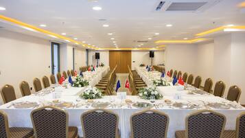 Un salón de conferencias con una larga mesa dispuesta para una reunión, flanqueada por filas de sillas y banderas de varios países.