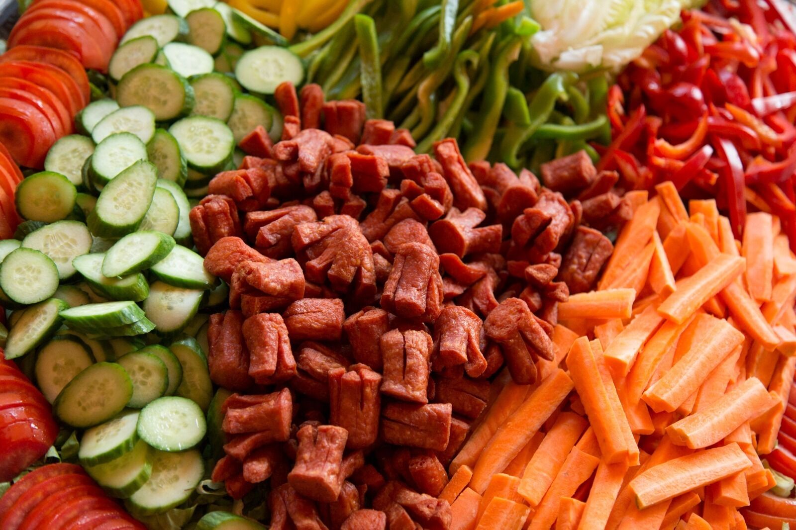 A variety of sliced vegetables including cucumbers, carrots, and tomatoes.