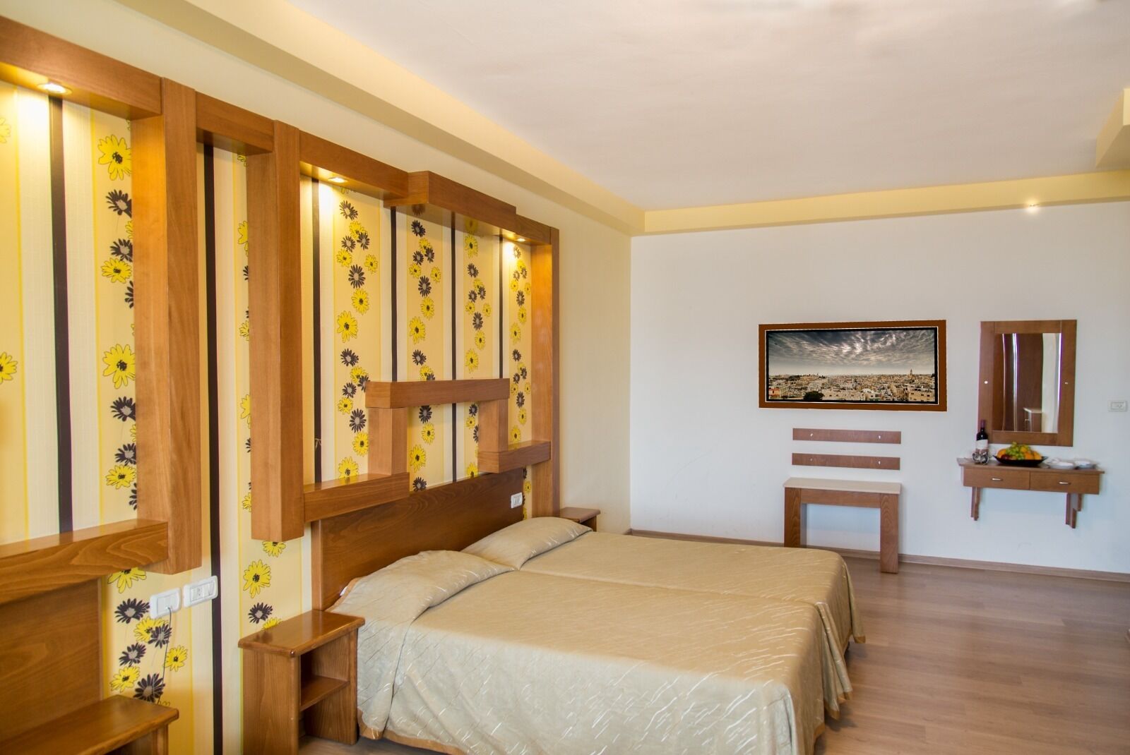 A bedroom with a bed, wooden headboard, a nightstand, a bedside table, a dresser, a framed picture on the wall, and a mirror.