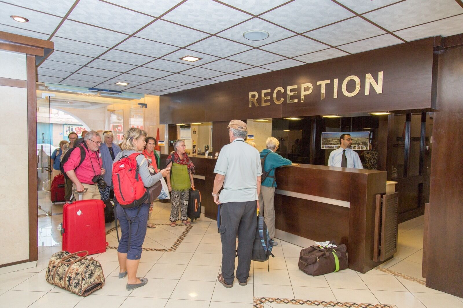 A reception area with a 'RECEPTION' sign, a reception desk, and people standing in line.