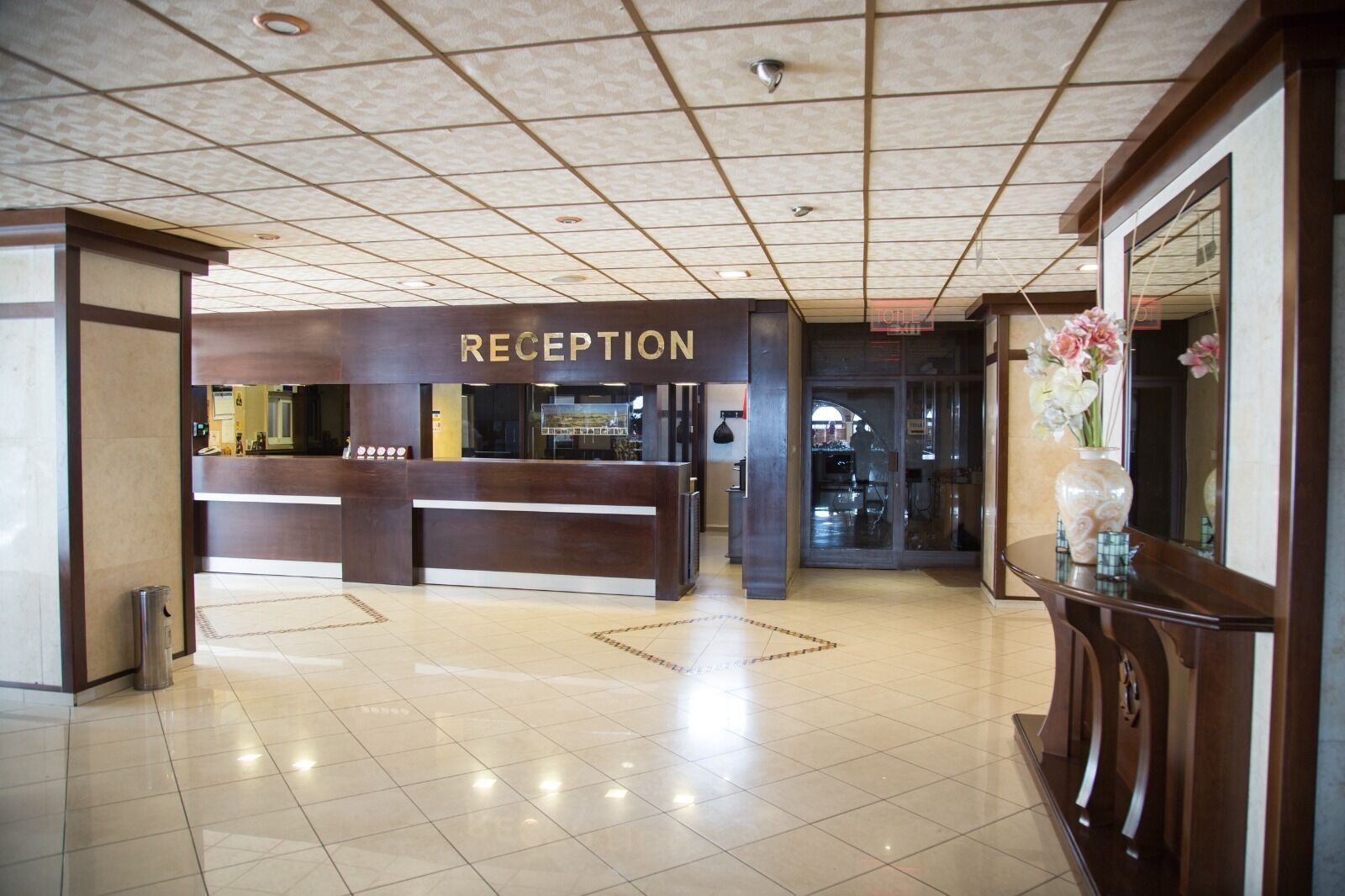 A reception area with a 'RECEPTION' sign, a tiled floor, and a large mirror on the right.