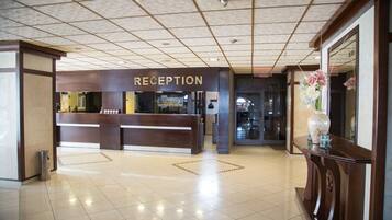A reception area with a 'RECEPTION' sign, a tiled floor, and a large mirror on the right.