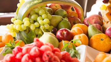 A variety of fresh fruits and vegetables, including grapes, apples, peaches, and oranges, displayed in a market setting.