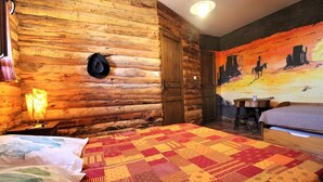 A log cabin room with a bed, a table, and a wall mural. - LES CHAMBRES DE L'OUEST (Longessaigne)