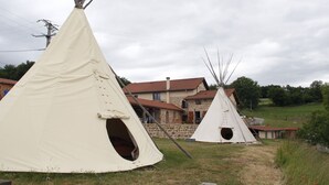 Three white teepees with open entrances, set on grass with a stone building in the background. - LES CHAMBRES DE L'OUEST (Longessaigne)