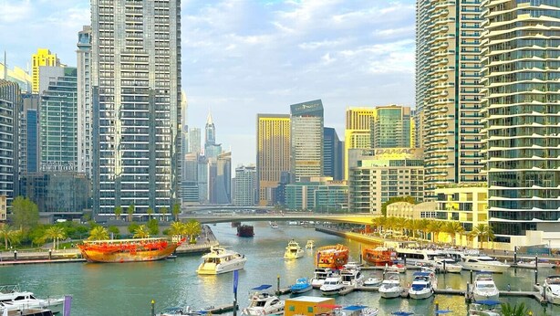 A marina with numerous boats docked, surrounded by high-rise buildings and palm trees. - Big Studio w/ Balcony and easy access to the Beach in Marina (Dubai)
