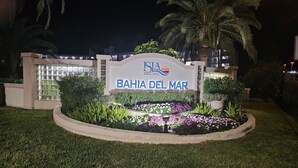 A sign for "Bahia Del Mar" with a landscaped garden and palm trees.