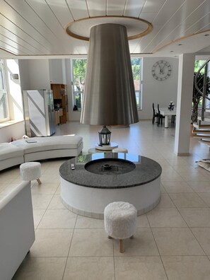 Cozy up by the fire in this inviting living area, featuring a circular seating arrangement and a stylish dining table.