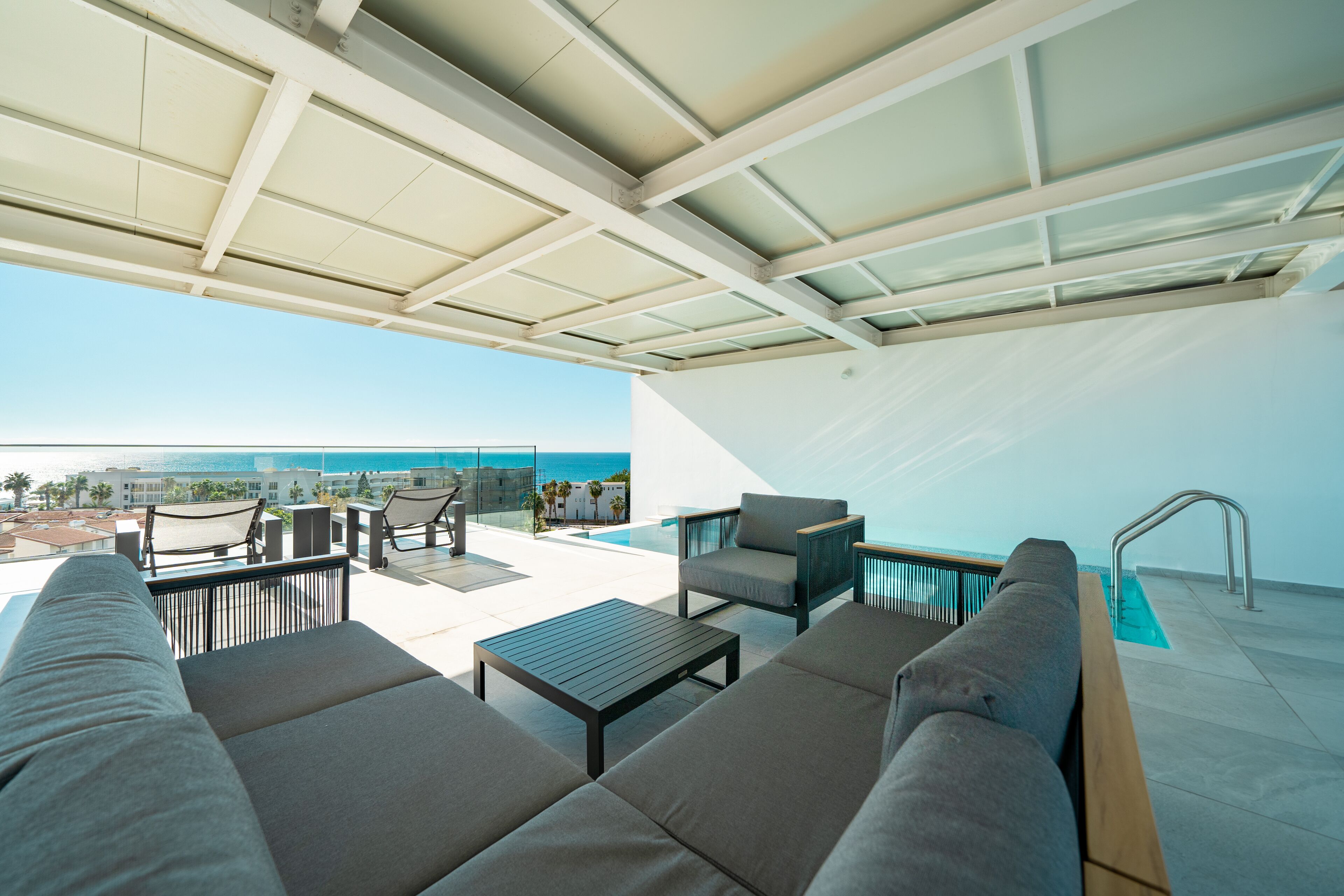 A rooftop terrace with a pool, outdoor seating, and a view of the ocean.