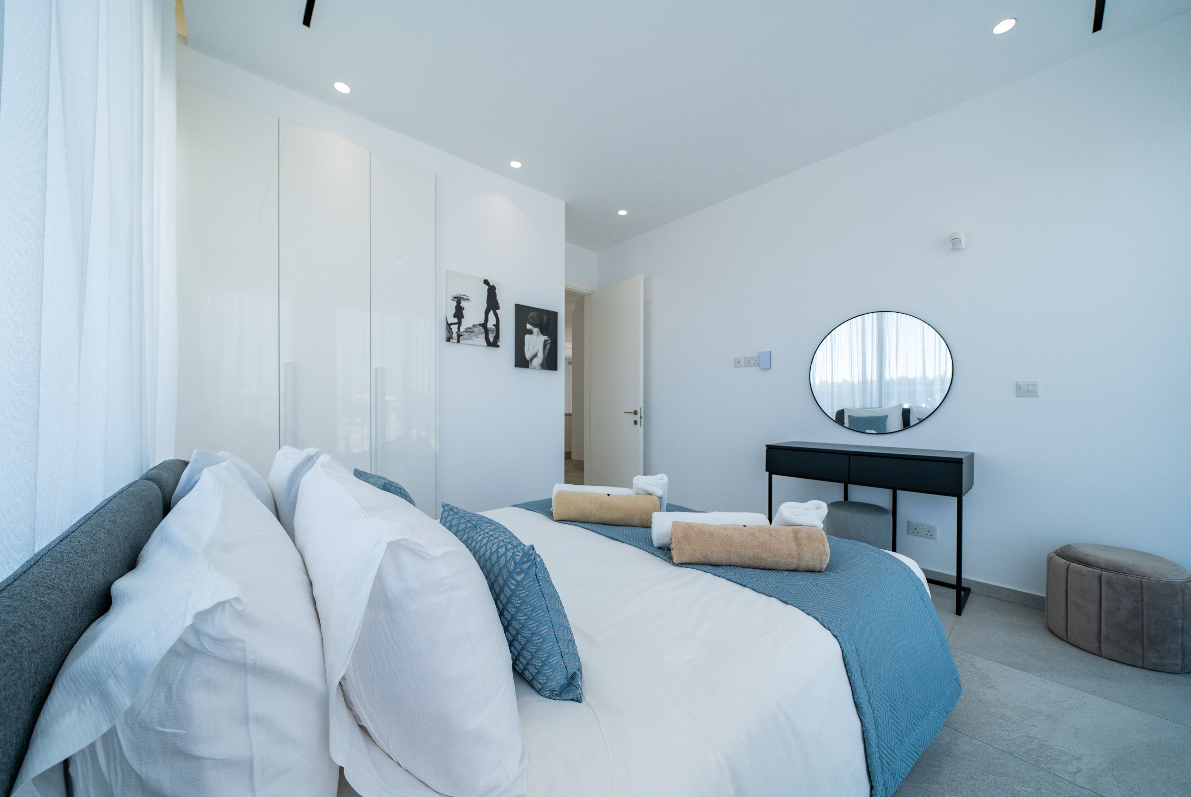 A modern hotel room with a large bed, a desk, and a mirror.