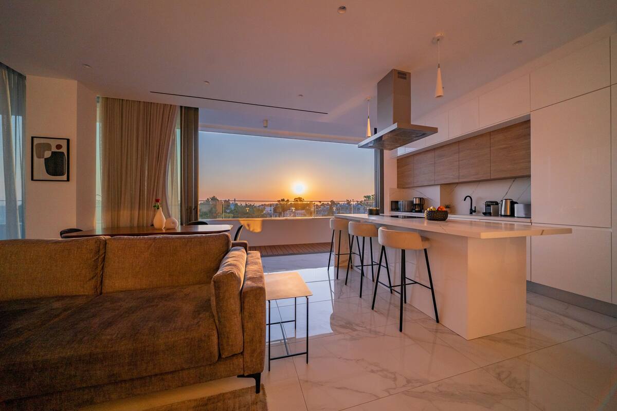 Una sala moderna con un sofá y una zona de comedor con taburetes.