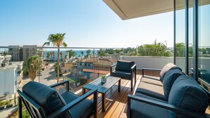 A balcony with a sofa, a small table, and a potted plant. - The Palmiers (Paphos)