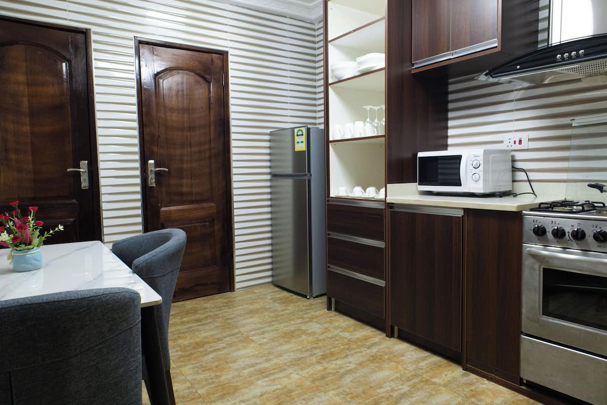 Uma cozinha compacta com geladeira, micro-ondas, forno e um espaço de refeições com mesa e cadeiras.