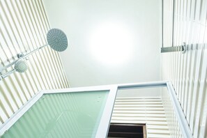 A bathroom with a shower, a glass door, and a window with blinds. - Jannah Villas - Ghana (Adentan)