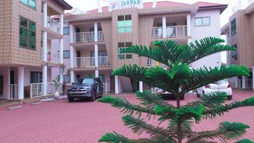 Experience the charm of Jannah Villas, featuring a brick facade, red-tiled entrance, and a lush garden with a majestic palm tree.
