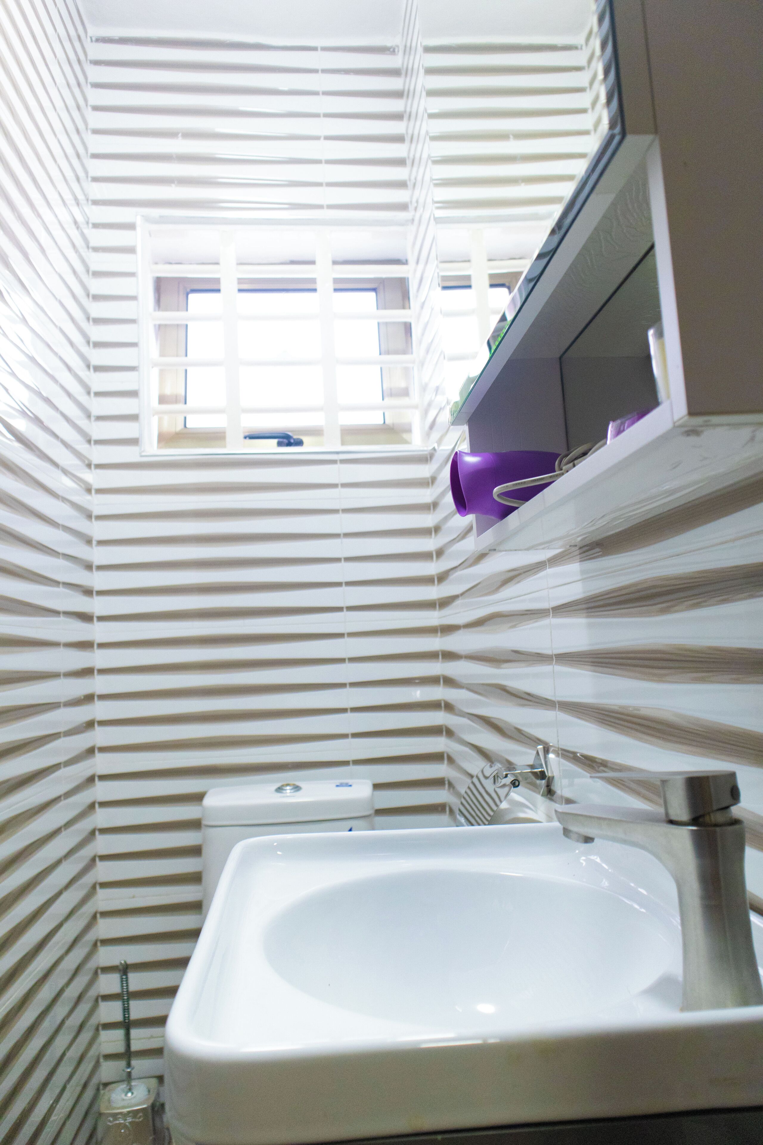 A bathroom with a white sink, a window, and striped walls.