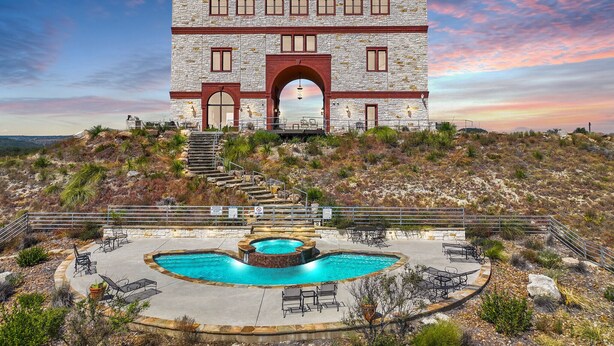 Ein Steinhaus mit Pool und Sitzgelegenheiten im Freien.
