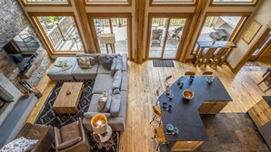 A spacious living area with a large sofa, a coffee table, and a dining table set with chairs. - Luxury 4BR Beehive Basin Home | Hot Tub, Mountain Views & Sleeps 13 (Big Sky)