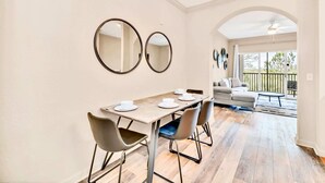 Un coin repas comprenant une table, des chaises et deux miroirs fixés au mur.