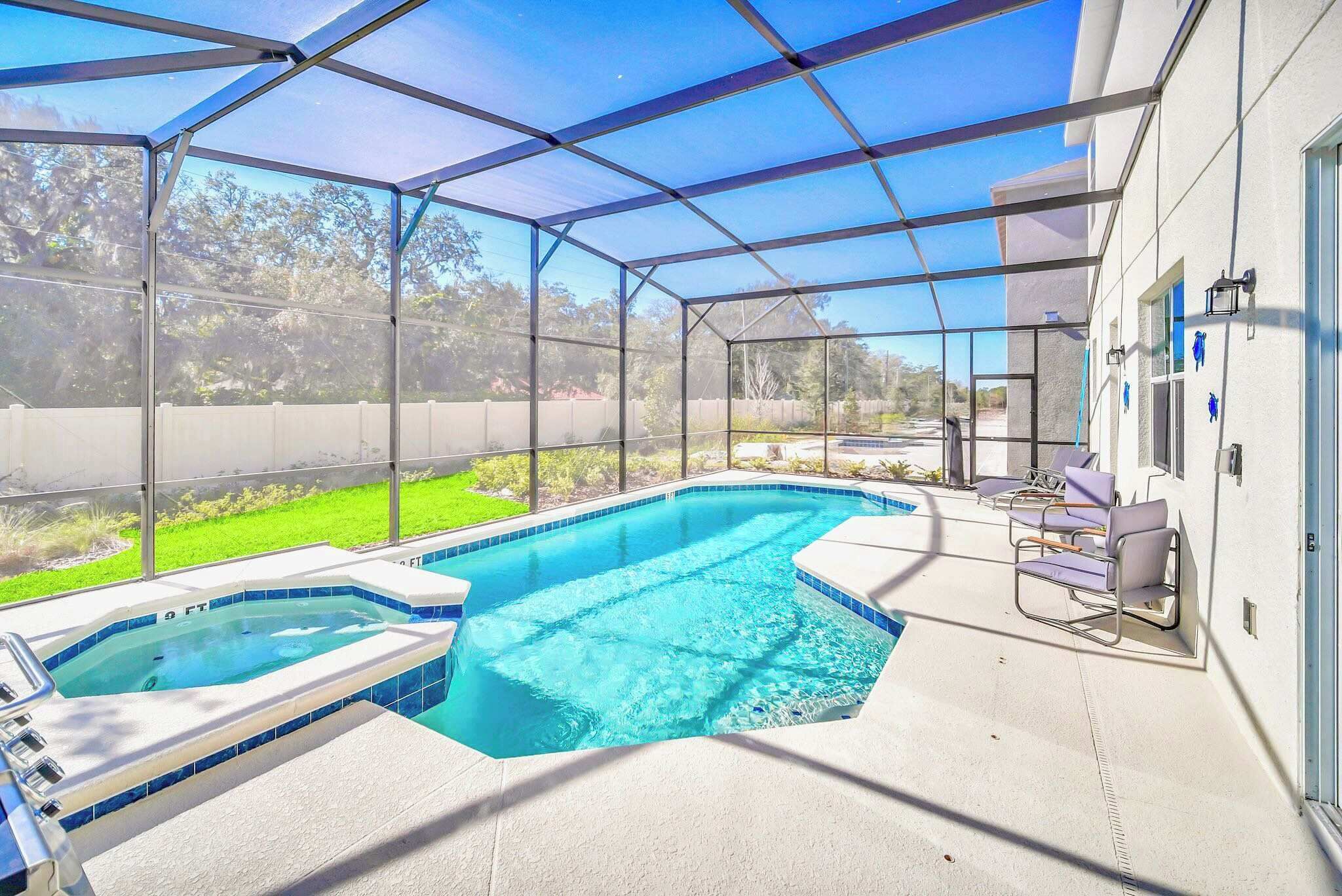 Piscina techada con jacuzzi, rodeada por un muro blanco y un cerramiento de vidrio.