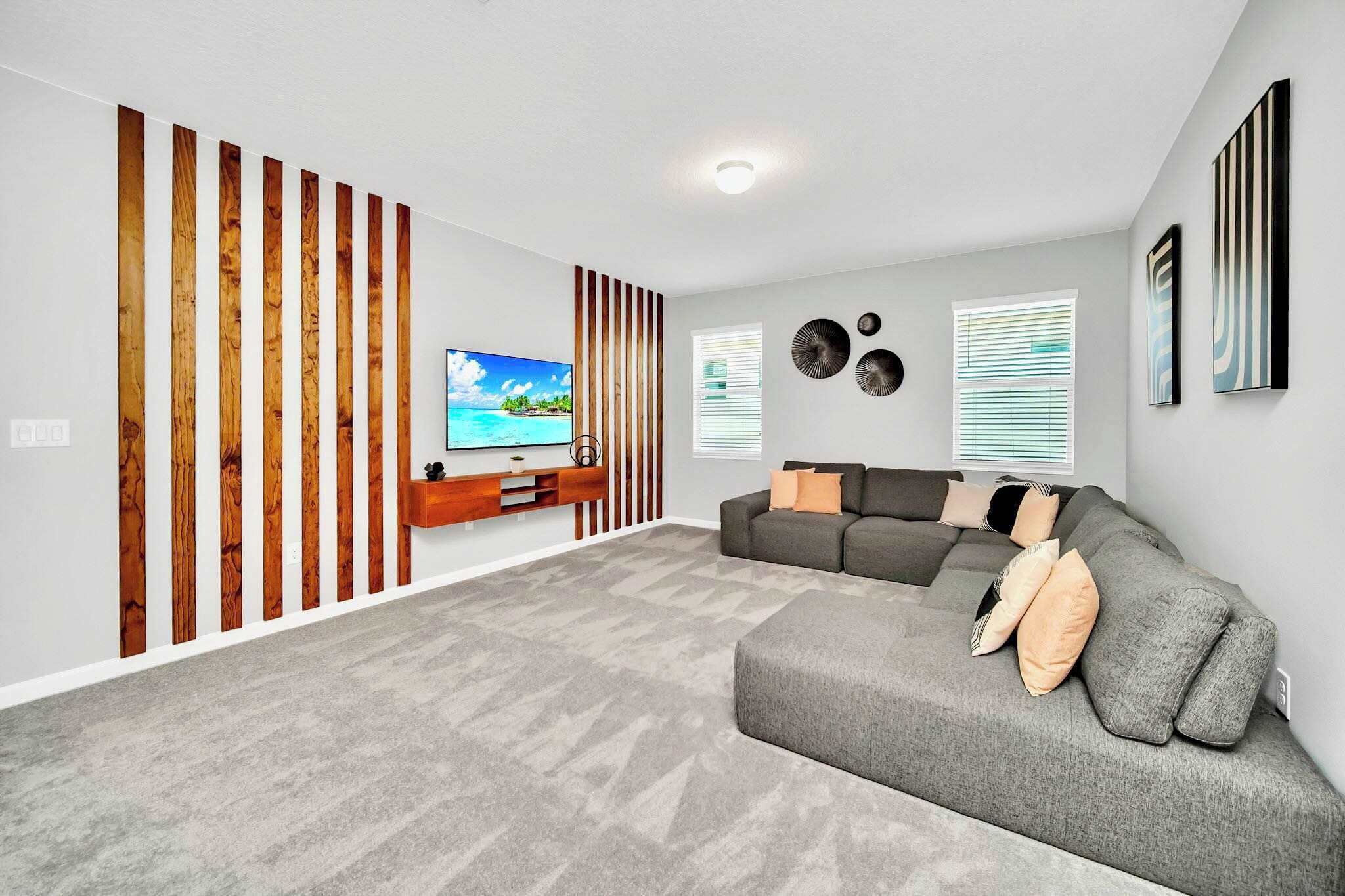 Una sala de estar moderna con un sofá modular, un televisor de pantalla plana y una pared decorativa de madera.