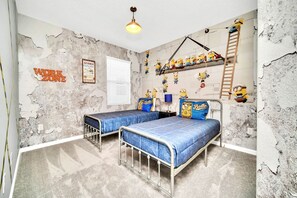 A bedroom with two metal bunk beds, a ceiling light, and a wall with peeling paint and Minion decorations. - Upstay: Modern Home w Pool, Games & BBQ—Sleeps 18 (Kissimmee)