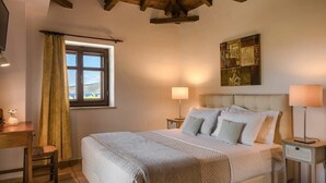A bedroom with a bed, bedside tables, a window with curtains, a painting on the wall, and a wooden ceiling. - Eleonas Houses - Kardamili's  Bianca Poolside Gem (Kardamyli)