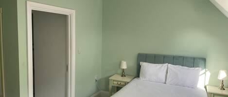 A bedroom with a bed, two bedside tables, and a door.