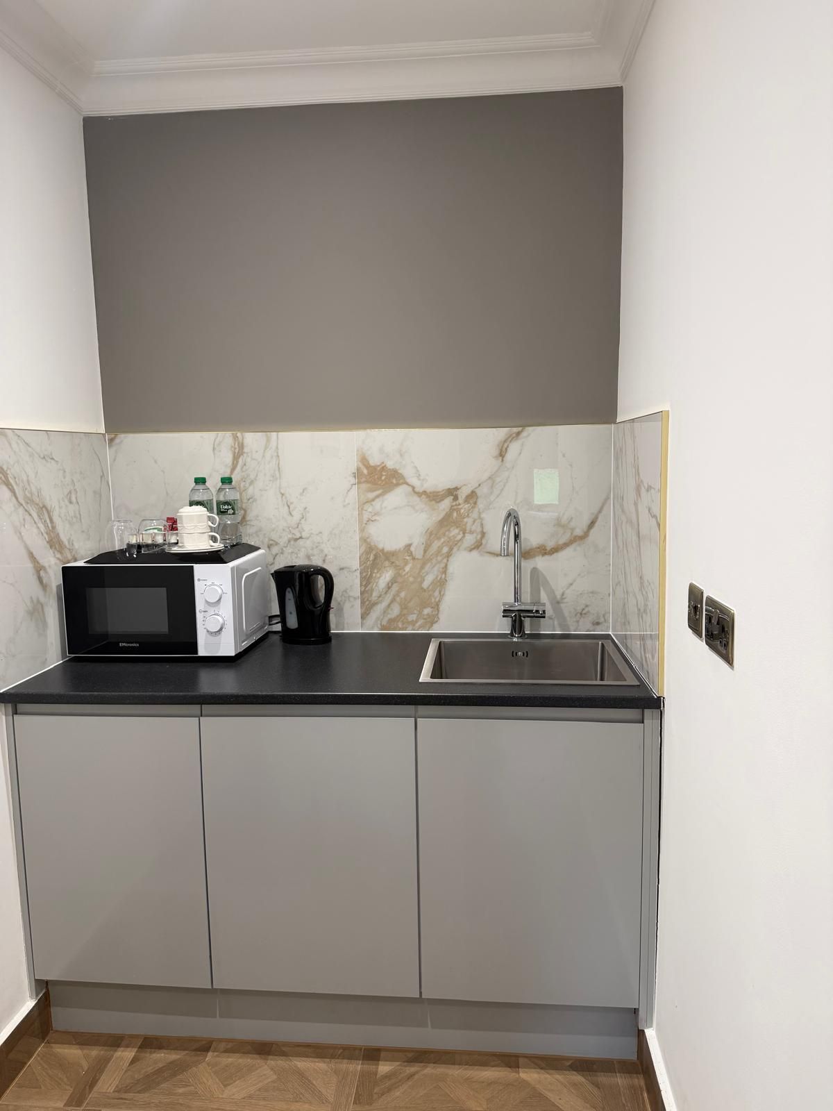 Cocina compacta con microondas, hervidor y pileta.