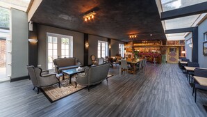A spacious lounge area with a bar, seating arrangements, and a view of the bar area. - The French Partridge (Northampton)