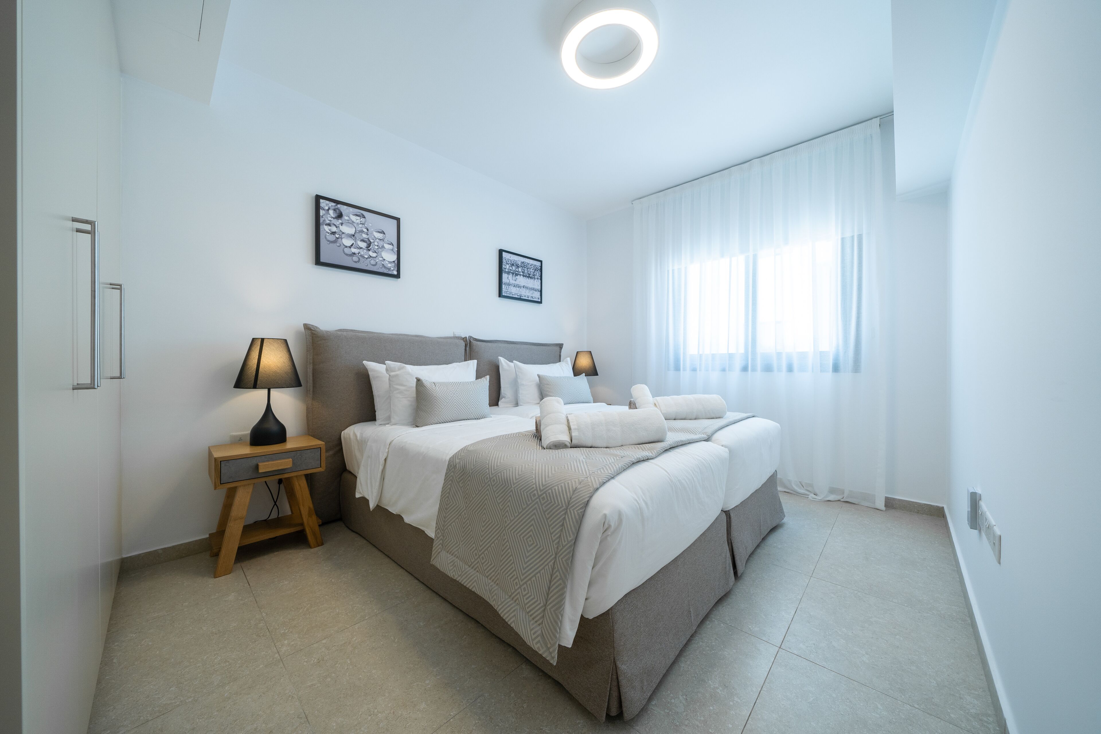 Una camera d'albergo moderna con un letto grande, due abat-jour, un comodino e una plafoniera.