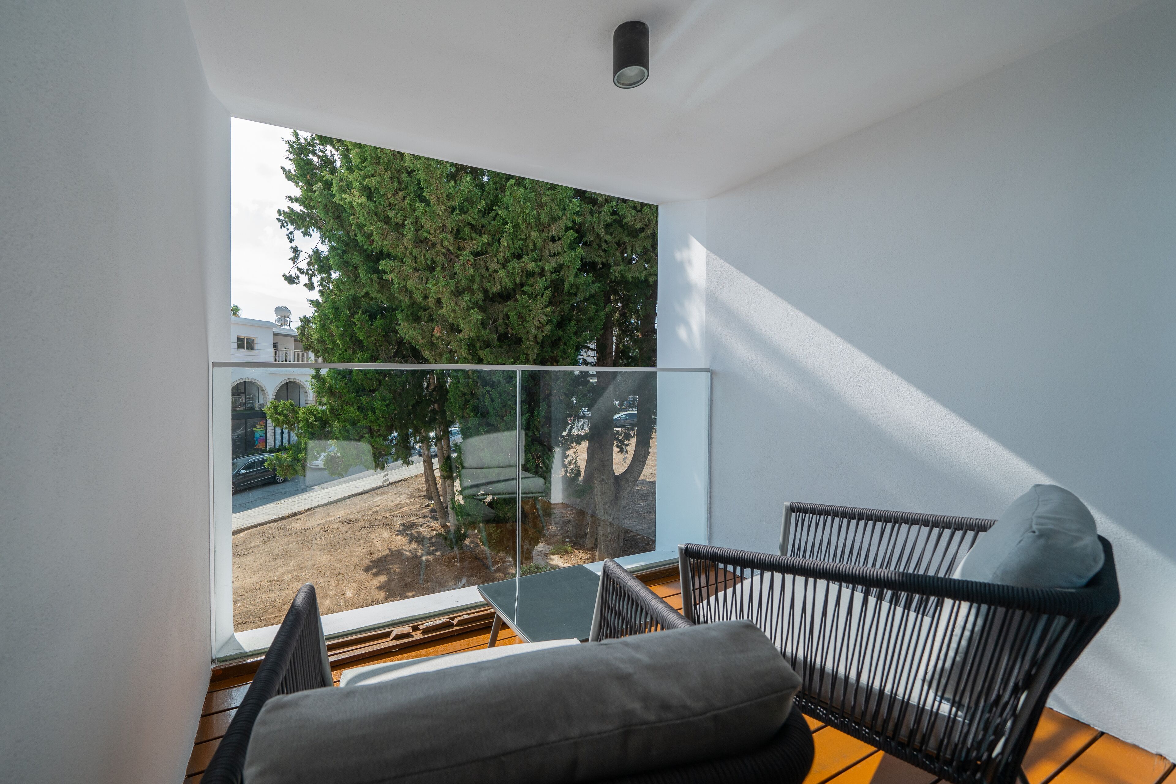 Una sala de estar moderna con un ventanal grande, un sofá y dos sillones.