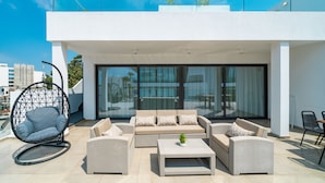 A modern outdoor living area with a sofa set, a hanging chair, and a coffee table. - Silver Park by Deserve (Paphos)