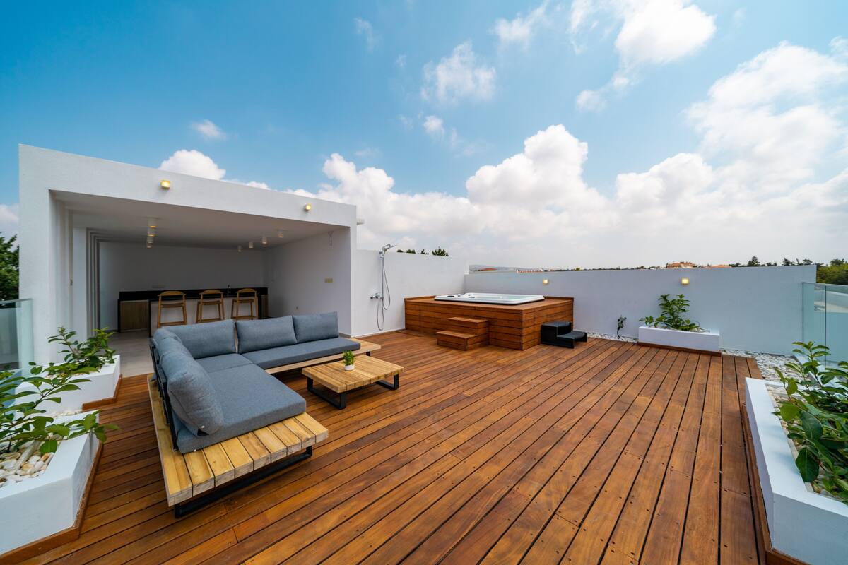Une terrasse en bois avec un canapé, une petite table et un jacuzzi.
