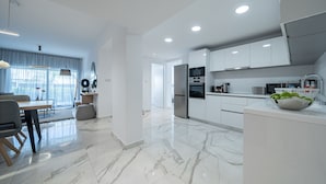 A modern kitchen with white cabinets, a refrigerator, an oven, and a microwave. - Silver Park by Deserve (Paphos)