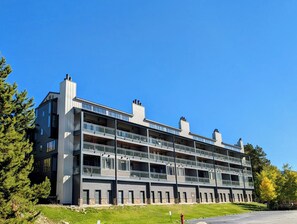 Un edificio de varios pisos con balcones, techo plano y cielo azul despejado.