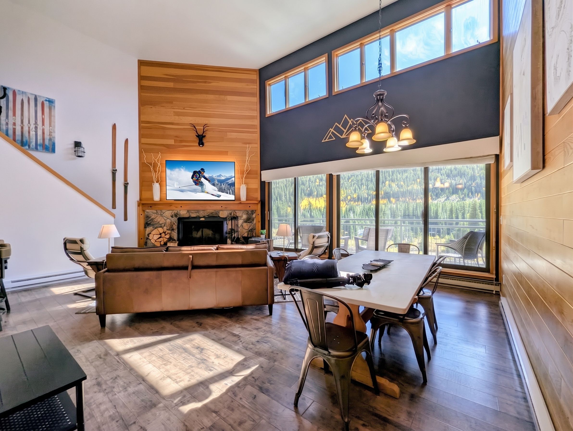 A spacious living area with a fireplace, a television mounted on the wall, and a dining table with chairs.
