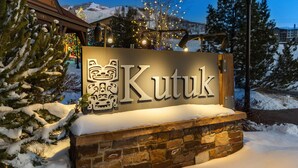 A sign with the name "Kutuk" in a stylized font, set against a stone wall with snow accumulation.