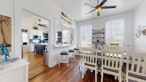 A spacious kitchen with white cabinets, a central island, and a dining area with a white fence and chairs. - 5 bedrooms, 2 1/2 bathrooms, sleeps 21 guests, and pet friendly. (Port Bolivar)