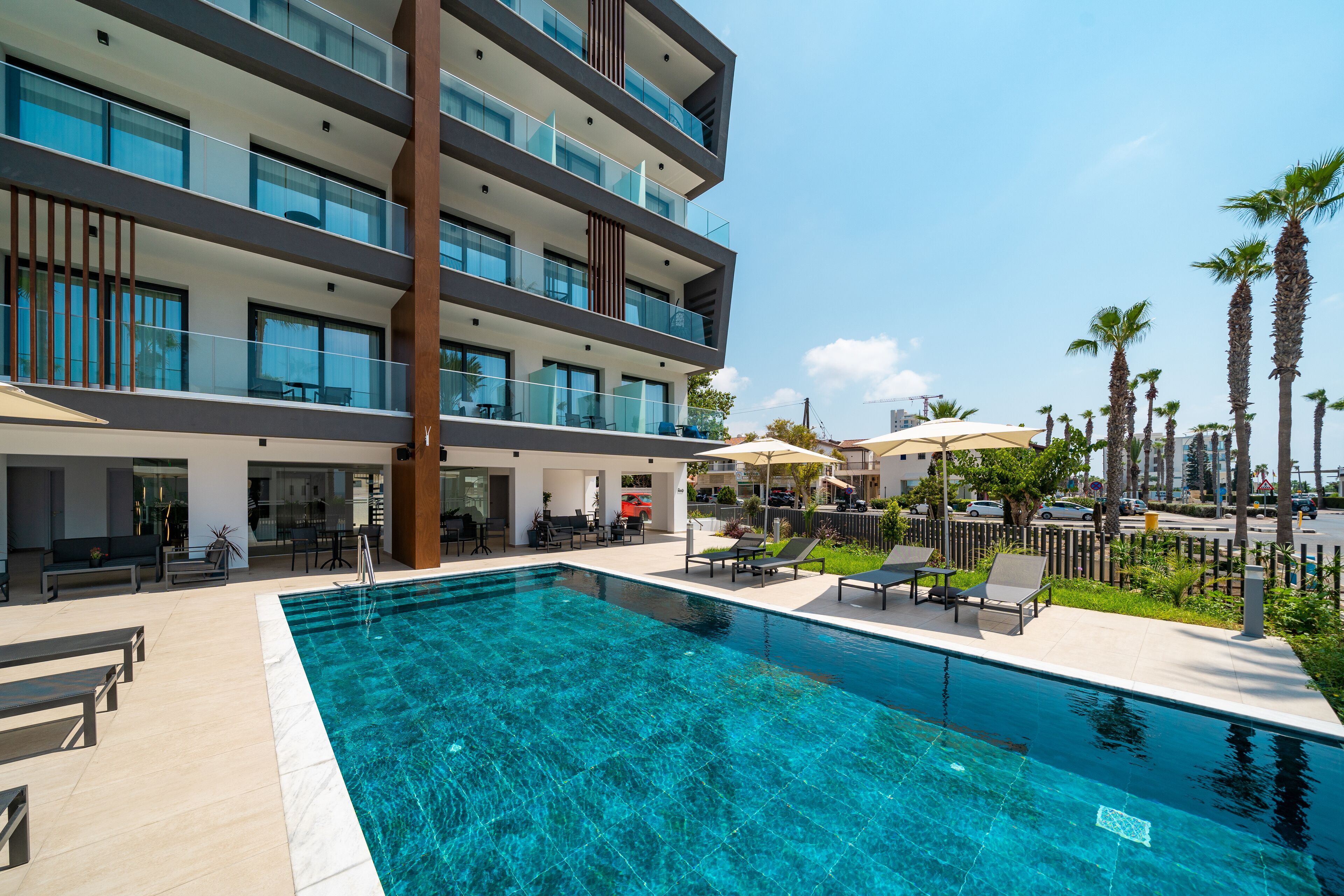 Un hotel moderno con piscina sul tetto, posti a sedere all'aperto e palme.