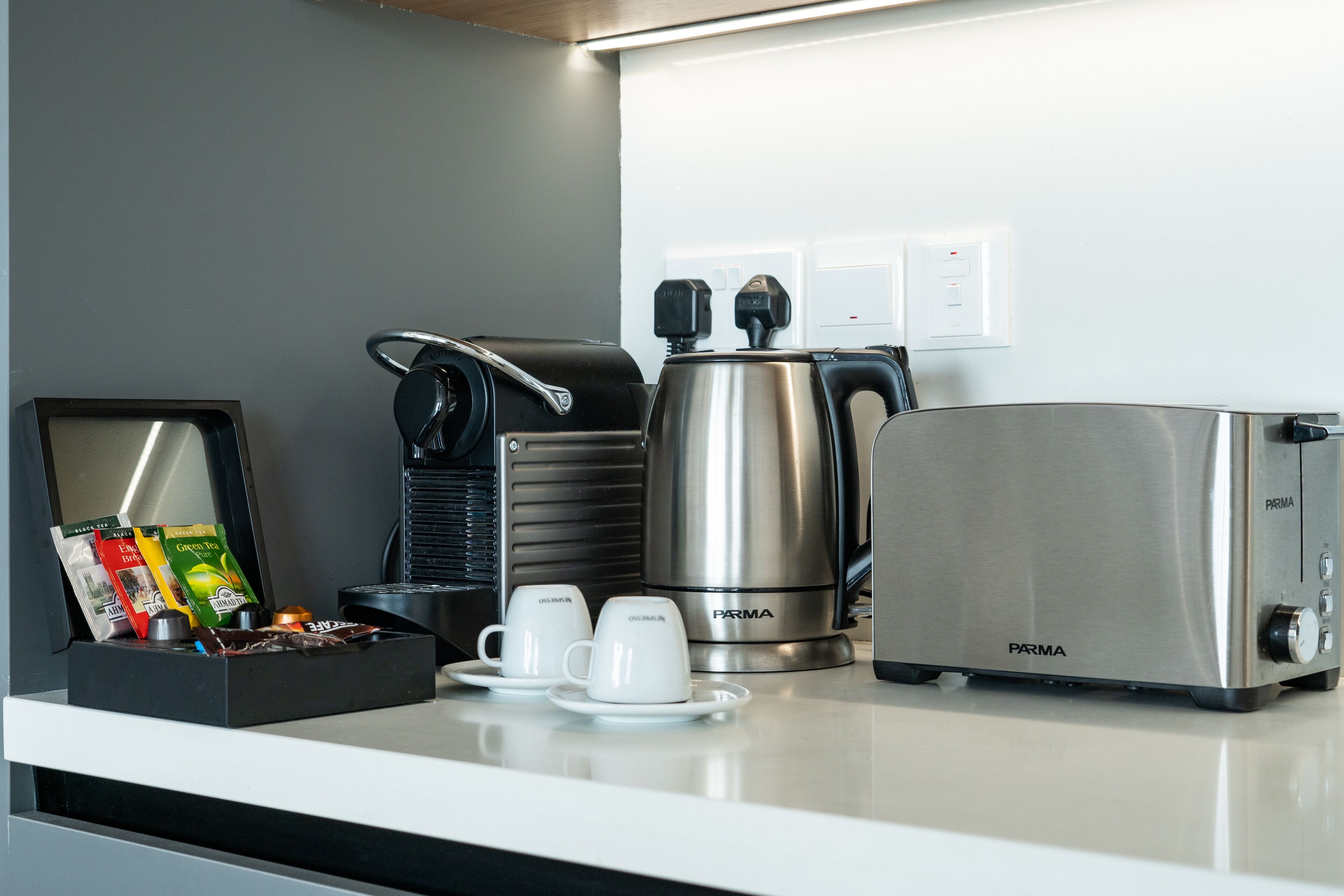Una cocina moderna con cafetera, tostadora y estación de café con tazas y sobres.