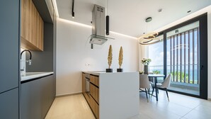 A modern kitchen with a central island, built-in appliances, and a dining area with a view. - Waterside by Deserve (Paphos)