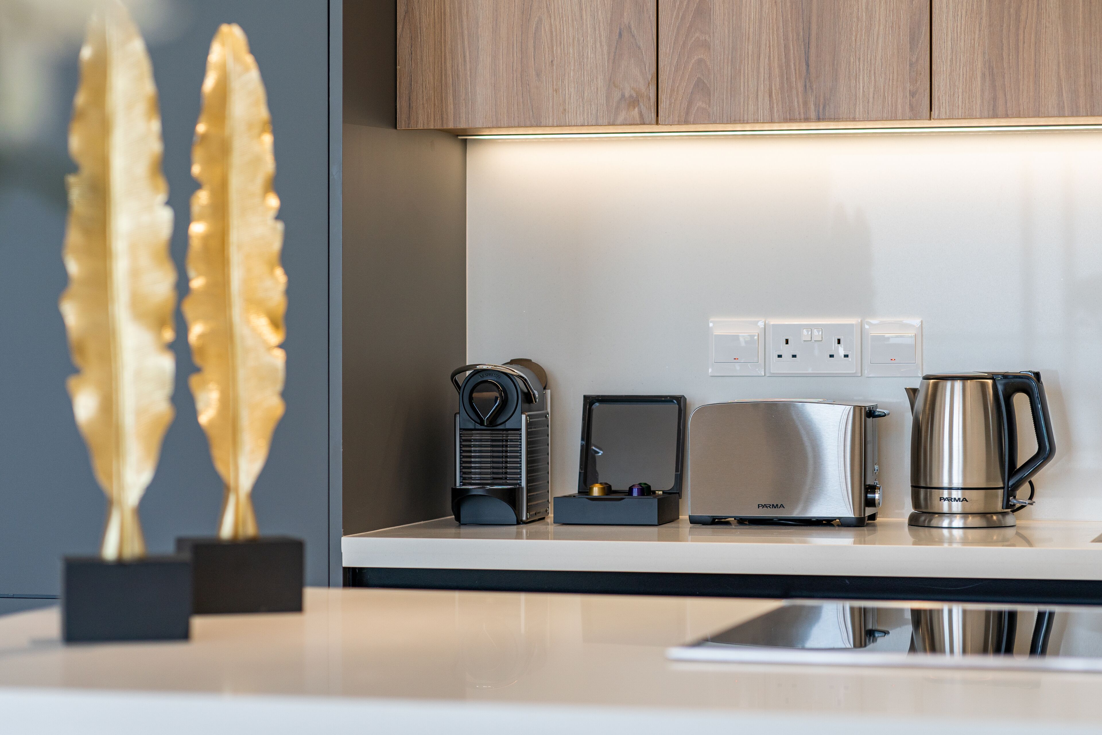 Une cuisine moderne équipée d’un plan de travail, d’une machine à café, d’un grille-pain et d’une prise électrique.