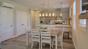 A modern kitchen with white cabinetry, a central island, and pendant lighting. - Vitamin Sea - Oyhut Bay Seaside Village (Ocean Shores)