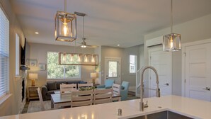 A modern kitchen with a central island, stainless steel sink, and pendant lighting. - Vitamin Sea - Oyhut Bay Seaside Village (Ocean Shores)