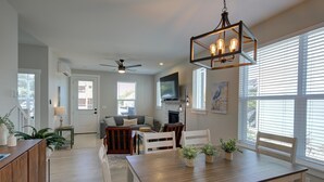 A modern kitchen with a dining area, wooden cabinets, a dining table, and a ceiling fan.
