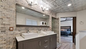 A bathroom with a double sink vanity, a large mirror, and a ceiling fan. - The Gemini House | Spacious Pinehurst Golf Retreat (Pinehurst)