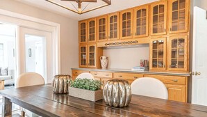 A dining area with a wooden table, chairs, and a kitchen with wooden cabinets. - The Gemini House | Spacious Pinehurst Golf Retreat (Pinehurst)