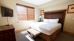 A hotel room with a large bed, a desk, a TV, and a window with blinds. - Silverado Lodge - 1 BR Suite, King Bed & Pool View by RedAwning (Park City)