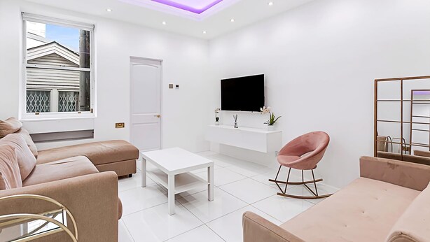 Ein modernes Wohnzimmer mit einer Couch, einem Couchtisch, einem Fernseher und einem Sessel.